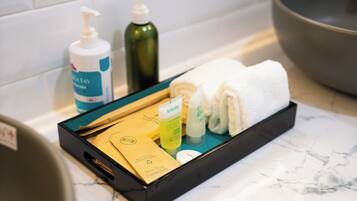 A bathroom with a black tray holding toiletries, a towel, and a bath mat.