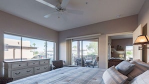 A bedroom with a large bed, a dresser, a chair, and a balcony with outdoor furniture. - Walk to Fountain Park! Ground-Floor Condo w/ Pool, Spa & Private Patio (Fountain Hills)