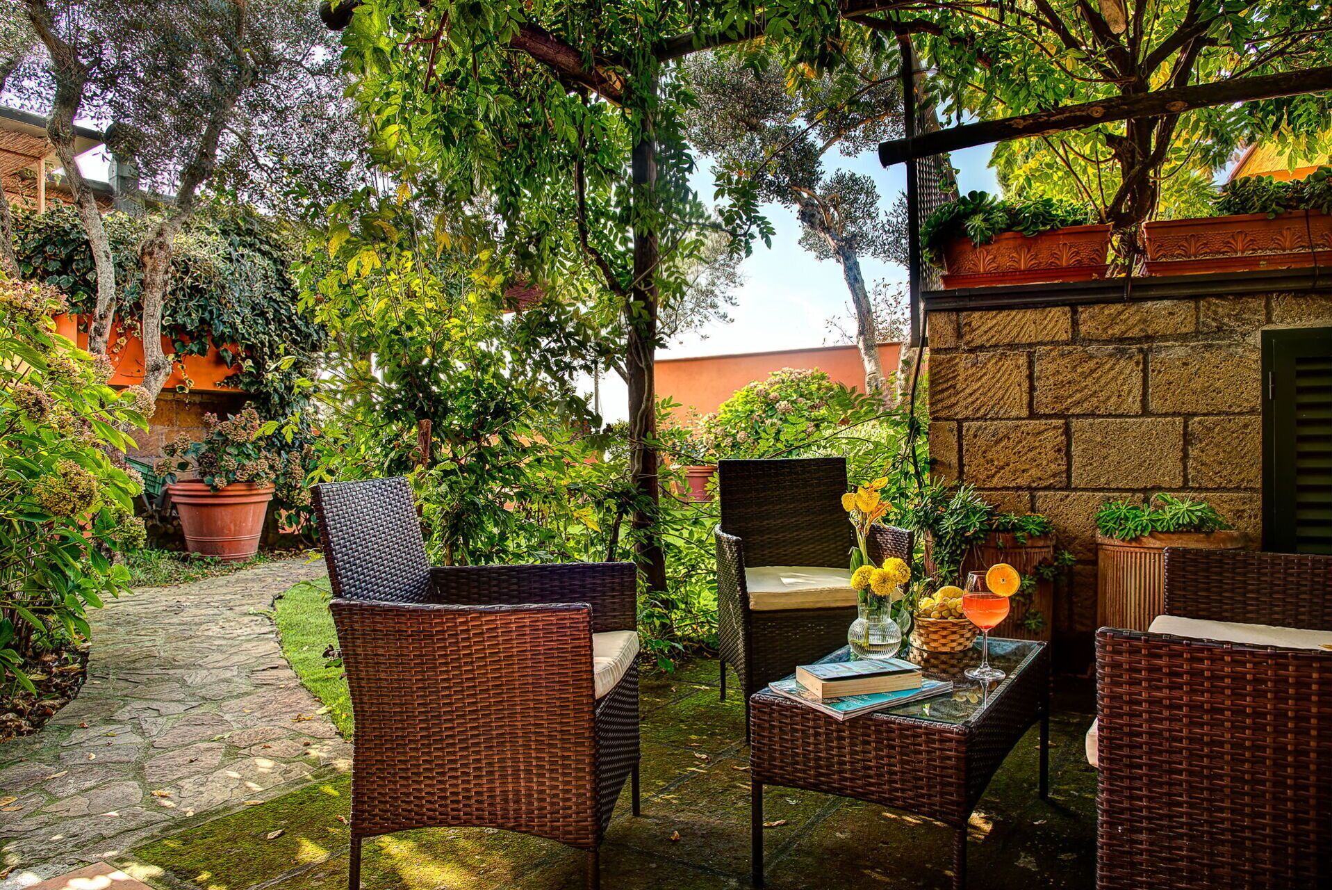 Un patio con mobiliario de mimbre, plantas en macetas y un camino de piedra.