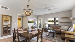 A spacious living room with a dining area, a ceiling fan, and a large window. - Ground Floor Condo Near Plaza & Fountain Park w/ Pool, Hot Tub & Private Patio (Fountain Hills)
