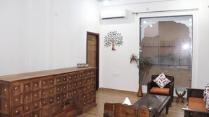 Een receptiebalie met een houten kastje met daarop 'RECEPTION', een groot raam met uitzicht en een decoratieve boom aan de muur.