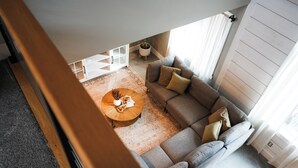 A modern living room with a sectional sofa, a round coffee table, and a white storage unit. - Apartment on Broadway St - L (Sugarcreek)