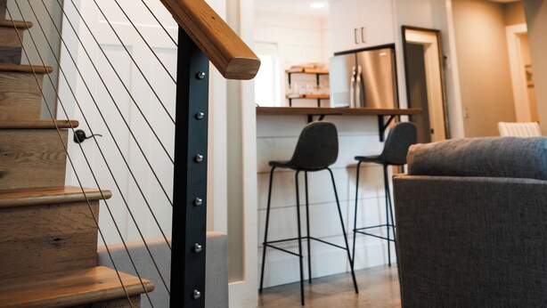 A modern interior with a wooden staircase, a kitchen area, and a seating space. - Apartment on Broadway St - L (Sugarcreek)