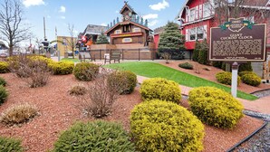 A historic building with a clock tower, surrounded by well-maintained gardens and a sign indicating it as a historical marker. - Apartment on Broadway St - L (Sugarcreek)