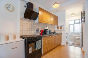 Une cuisine équipée d’une cuisinière, d’un four, d’un four à micro-ondes et de meubles de rangement en bois.