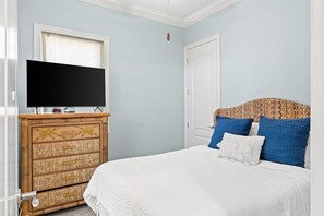 A bedroom with a bed, a television on a dresser, and a door.