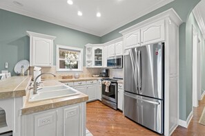 A modern kitchen with white cabinetry, stainless steel appliances, and a beige countertop.