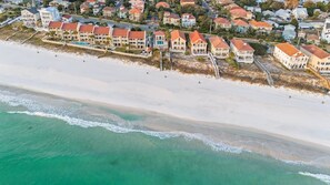A coastal residential area with beachfront properties, a sandy beach, and ocean waves.