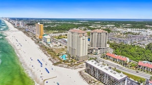 Un hotel costero con varios edificios altos, una playa y una piscina.