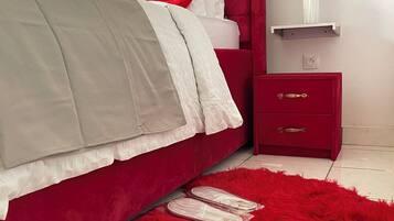 Ein Schlafzimmer mit einem roten Bett, einem roten Nachttisch und einem roten, flauschigen Teppich.