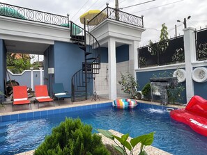 A swimming pool with a spiral staircase, lounge chairs, and a small waterfall feature. - RESIDENCE HMR Douala - Lendi (Douala)