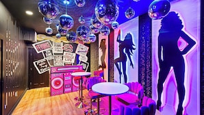 Een kamer met discoballen, neonborden en een silhouetmuur.