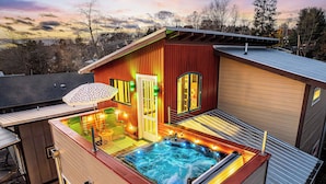 Een hottub op een dak terras met een houten buitenkant en uitzicht op het omliggende landschap.