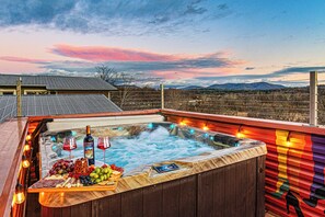 A hot tub with a wooden deck, surrounded by a wooden fence, and a scenic view of mountains in the background. - Decadent W Asheville Home, Rooftop Hot Tub & Views (Asheville)