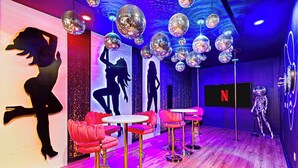 Een dansstudio met spiegelende discoballen, rode barstoelen en een 'Netflix'-bord aan de muur.