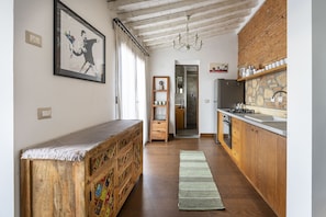 A kitchen with wooden cabinets, a built-in stove, and a hanging light fixture. - Fiesolana 27 Glass in Firenze (Florence)