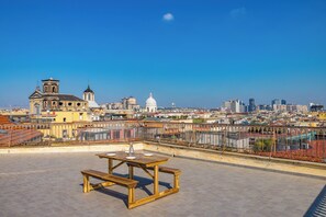 A rooftop terrace with a wooden table and benches, overlooking a cityscape with historic buildings and modern skyscrapers. - Un Terrazzo Panoramico su Napoli by Wonderful Italy (Naples)