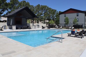 A swimming pool with a lounge area, a covered seating area, and a building with a red roof. - Inspired by the energy of live music, Amp'd Up combines modern comfort with thoughtful musical touches to create a stay that's memorable without sacrificing relaxation. (Rogers)