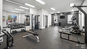 Un gimnasio con diversos equipos de ejercicio, incluyendo mancuernas, un banco y máquinas de cardio.