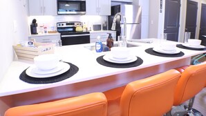 A modern kitchen with white cabinets, a microwave, stove, and a refrigerator. - Deluxe 2BR with king suites & pool near the Walmart NWA Championship. (Rogers)