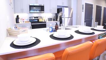 A modern kitchen with white cabinets, a microwave, stove, and a refrigerator.