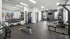 A gym with various exercise equipment, including dumbbells, a bench, and cardio machines. - Deluxe 2BR with king suites & pool near the Walmart NWA Championship. (Rogers)