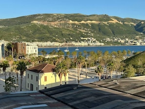 A coastal cityscape with a view of the sea, palm trees, and buildings.
