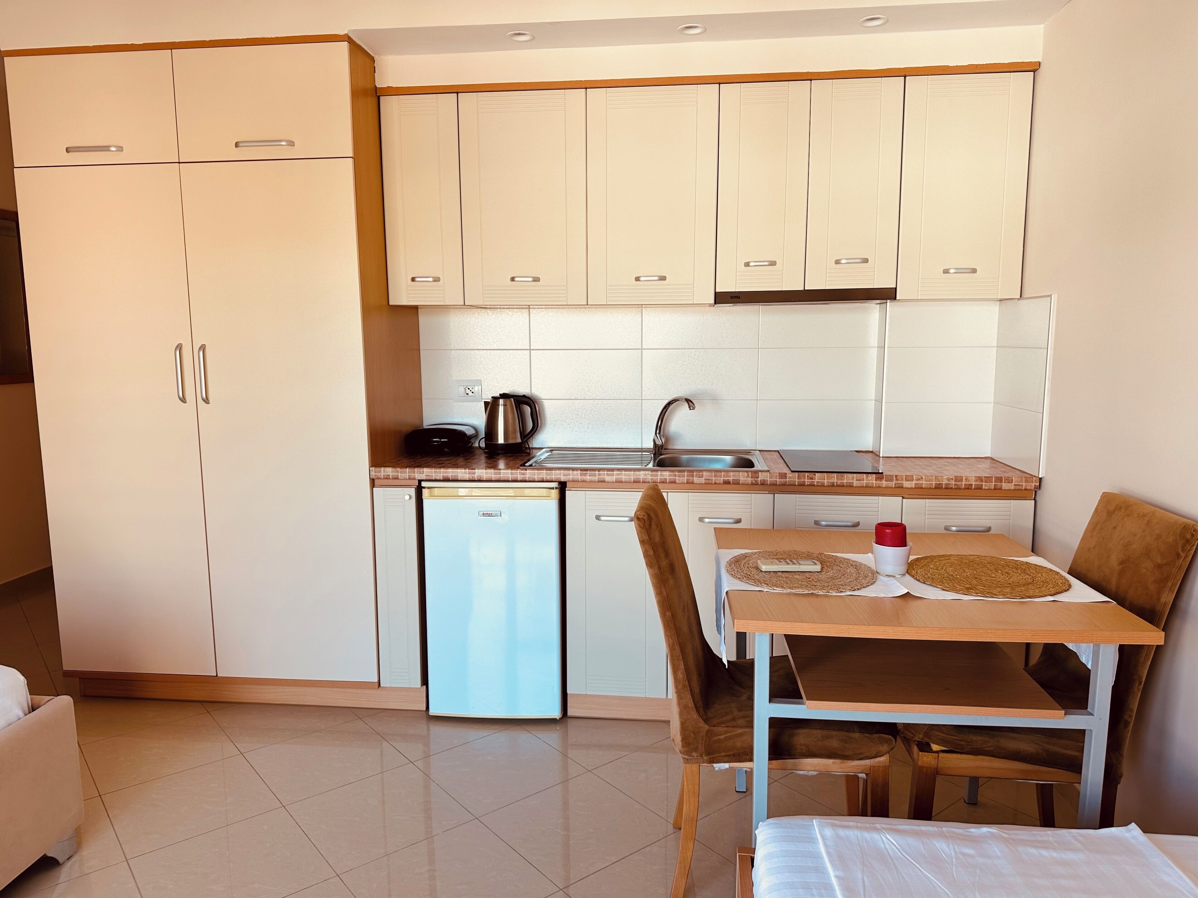 A compact kitchen with a dishwasher, a sink, and a dining area with a table and chairs.