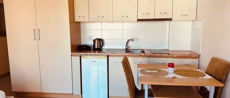 A compact kitchen with a dishwasher, a sink, and a dining area with a table and chairs.