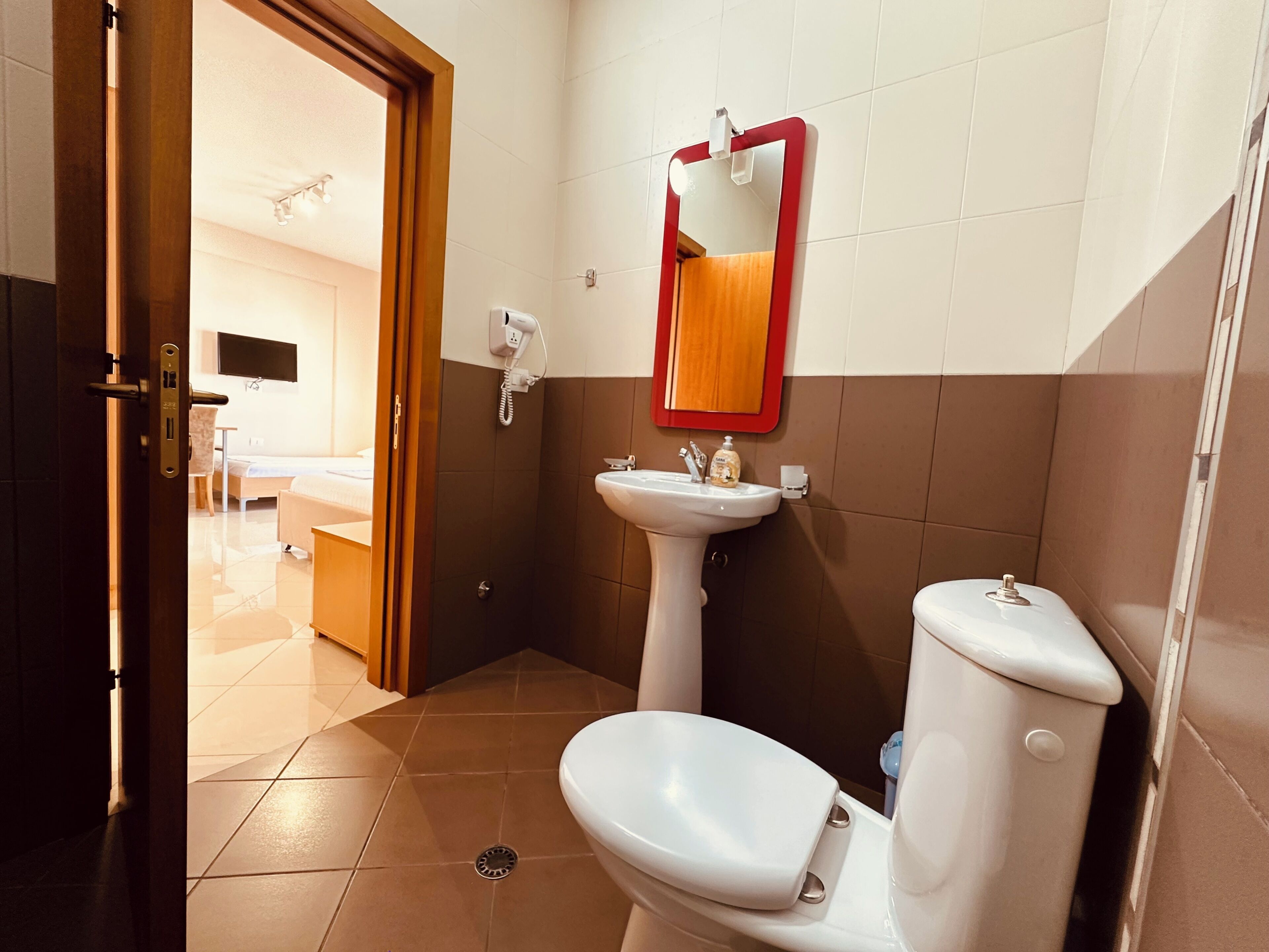 A bathroom with a toilet, sink, and mirror.