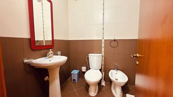 Ein Badezimmer mit Waschbecken, Toilette, Bidet und Spiegel.