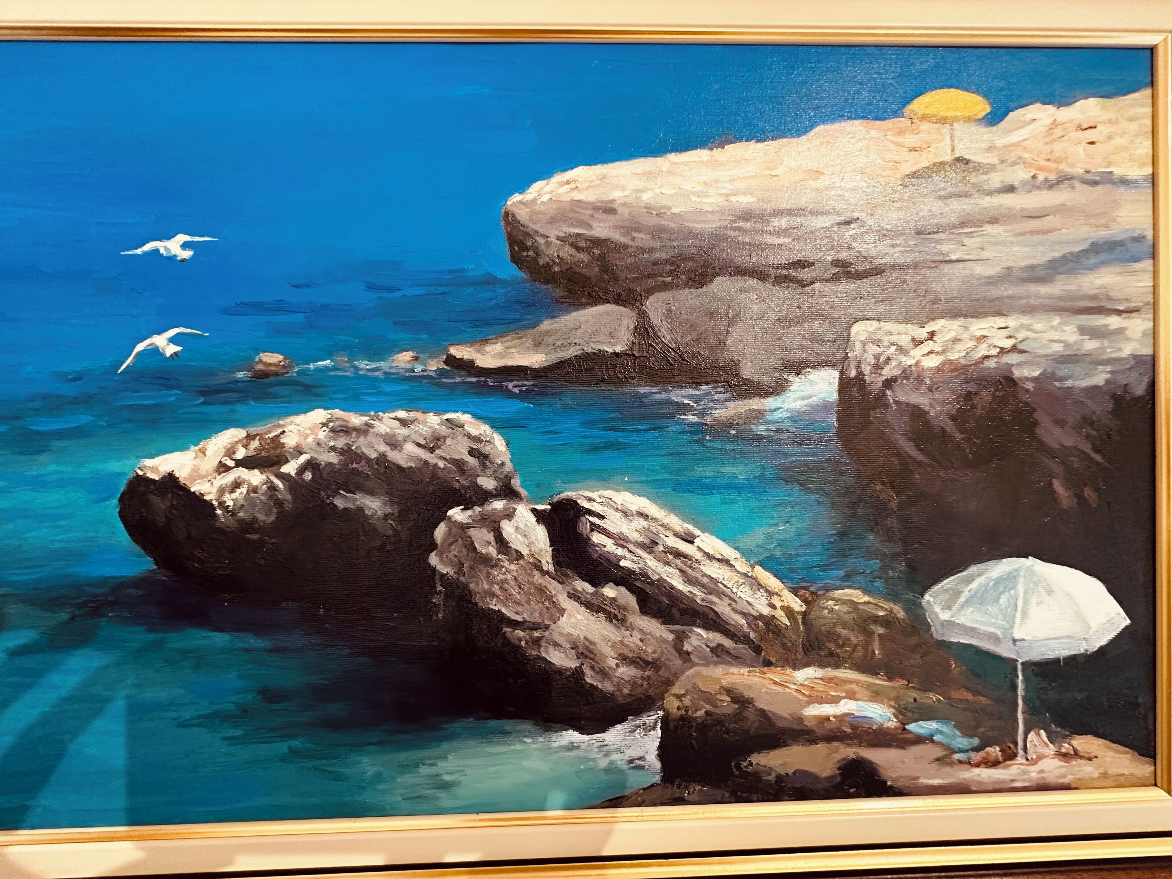 A painting of a coastal scene with rocks, clear blue water, and a white umbrella.