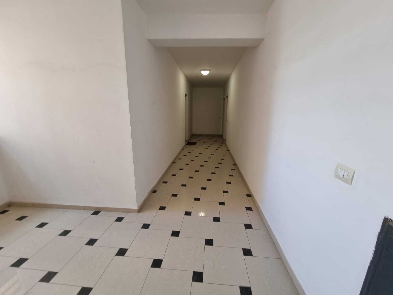 A narrow hallway with a tiled floor and white walls.