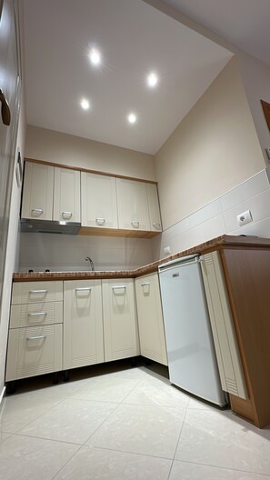 A kitchen with white cabinets, a built-in oven, and a tiled backsplash. - Thoma's K Studios (Vlorë)