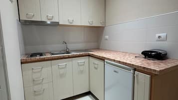 A kitchen with white cabinets, a sink, a stove, and a dishwasher.
