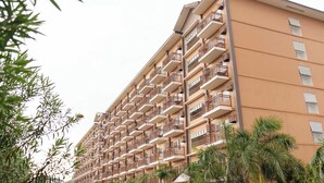 A multi-story hotel with balconies and a beige facade.