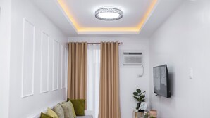A modern living room with a sofa, curtains, a TV, and a small table with decorative items.