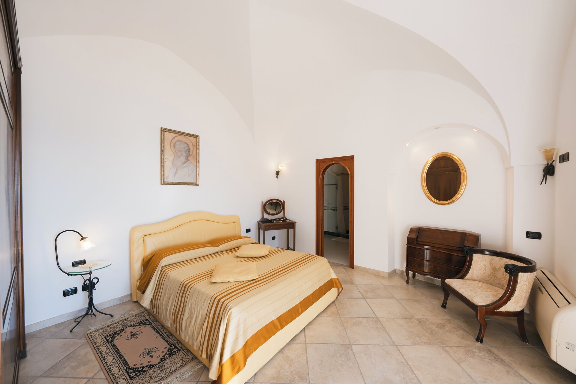 A bedroom with a bed, a chair, a dresser, a mirror, and a lamp.