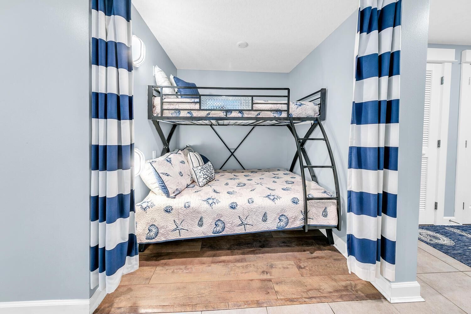 Dormitorio con literas de temática náutica, con cortinas a rayas y una colcha estampada.