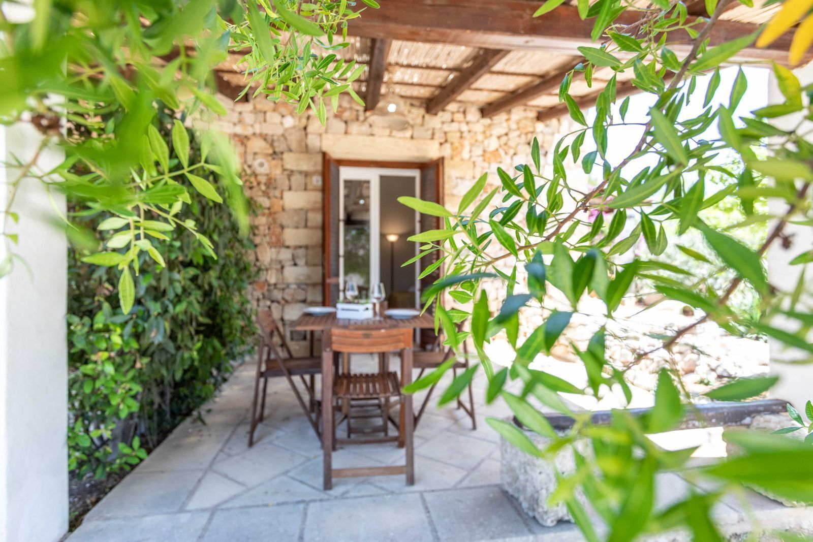 A stone building with a wooden table and chairs in a covered outdoor area.