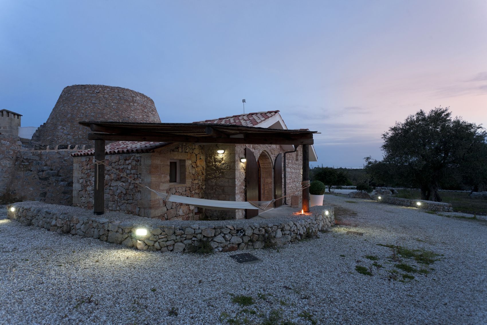 Un bâtiment en pierre doté d’un porche couvert et d’un hamac.
