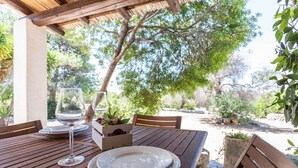 An outdoor wooden table with a glass of water, plates, and a small plant box.