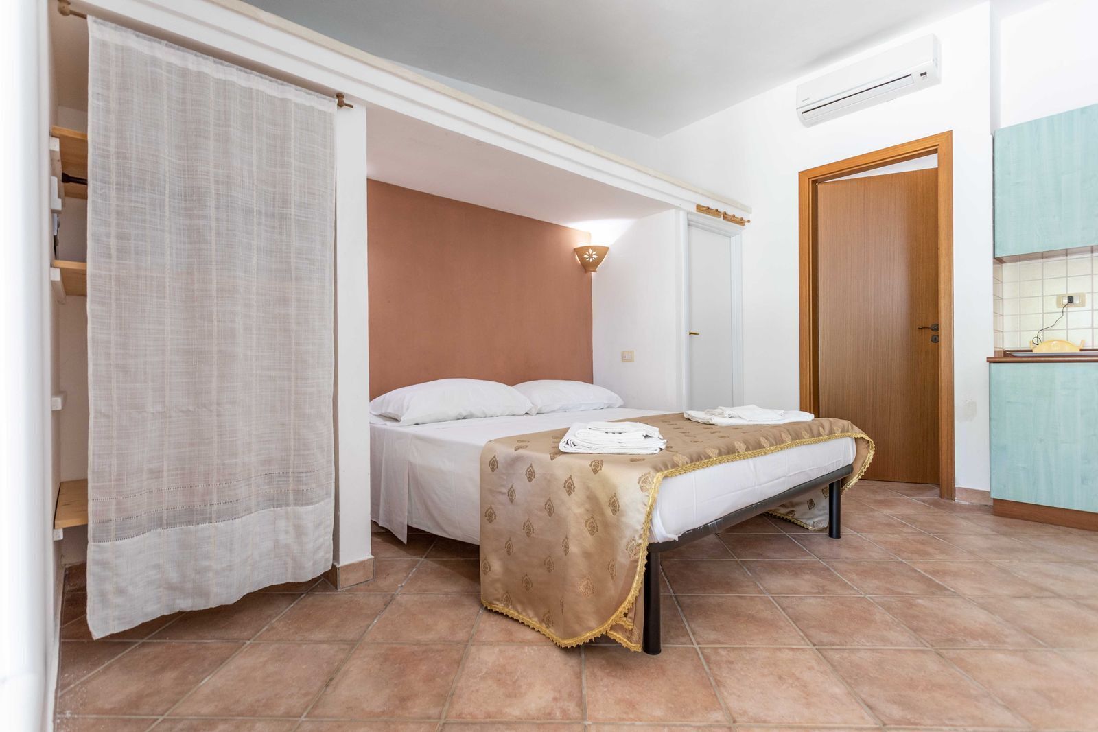 Una camera da letto con un letto, un comodino, un armadio e un bagno con lavandino e specchio.