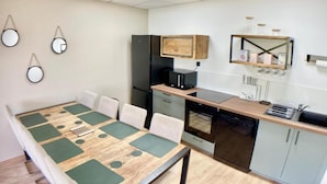 A modern kitchen with a dining table, chairs, a refrigerator, an oven, and a dishwasher. - New house Ovalie Montpellier near Stade de Rugby (Montpellier)