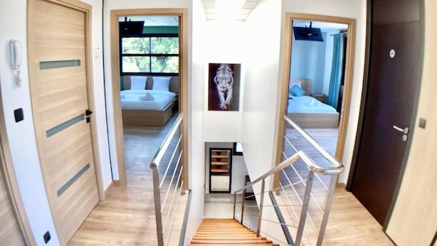 A modern hotel hallway with wooden floors, a central staircase, and doors leading to rooms. - New house Ovalie Montpellier near Stade de Rugby (Montpellier)