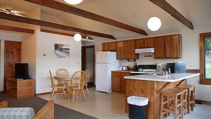 Una cocina compacta con armarios de madera, una isla central y una zona de comedor con sillas.