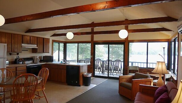 Una cocina amplia con armarios de madera, un comedor con sillas y un gran ventanal con vistas a una terraza.