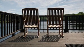 Two wooden chairs on a wooden deck with a railing, overlooking a body of water. - Come stay at our four season resort! (Weare)