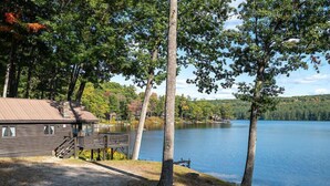 A cabin with a dock extending into a lake, surrounded by trees and a clear sky. - Come stay at our four season resort! (Weare)