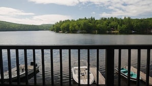A lake with boats docked on a wooden pier, surrounded by trees and a clear sky. - Come stay at our four season resort! (Weare)